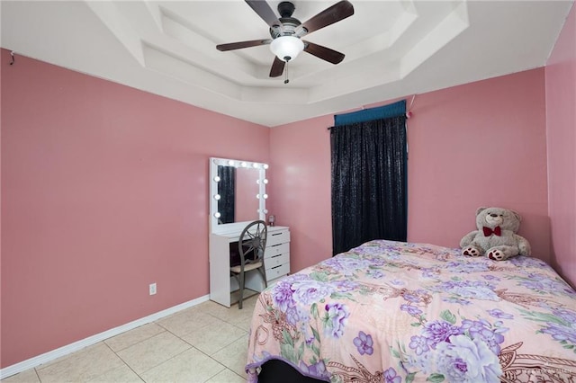 bedroom with light tile patterned floors, a tray ceiling, and ceiling fan