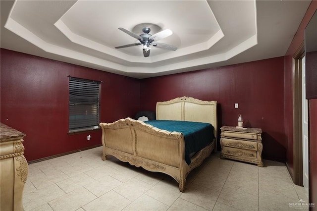 tiled bedroom with a tray ceiling and ceiling fan