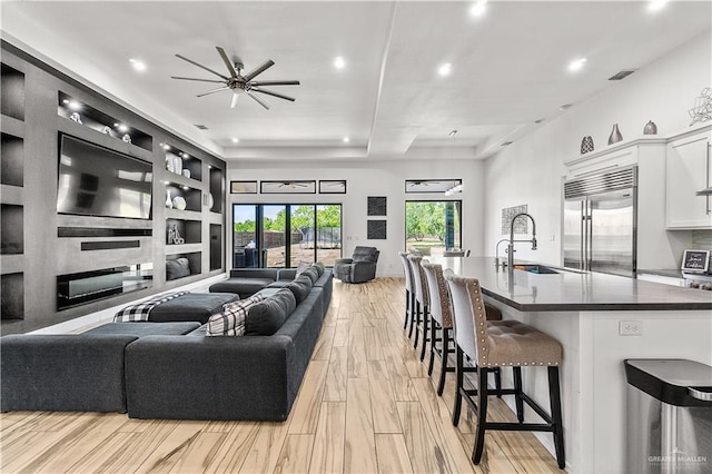 living room with light wood-style flooring, a ceiling fan, visible vents, and recessed lighting