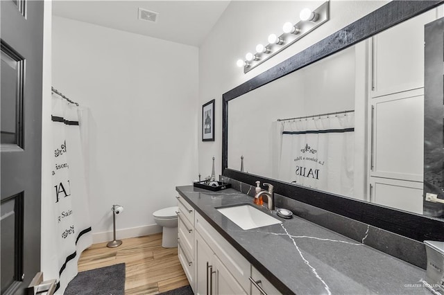 bathroom featuring visible vents, baseboards, toilet, vanity, and wood finished floors