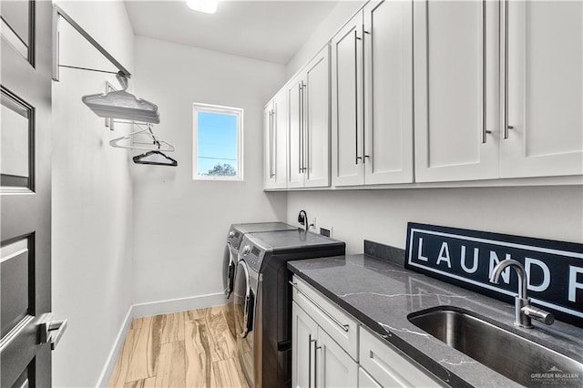 washroom with baseboards, washing machine and dryer, a sink, and cabinet space