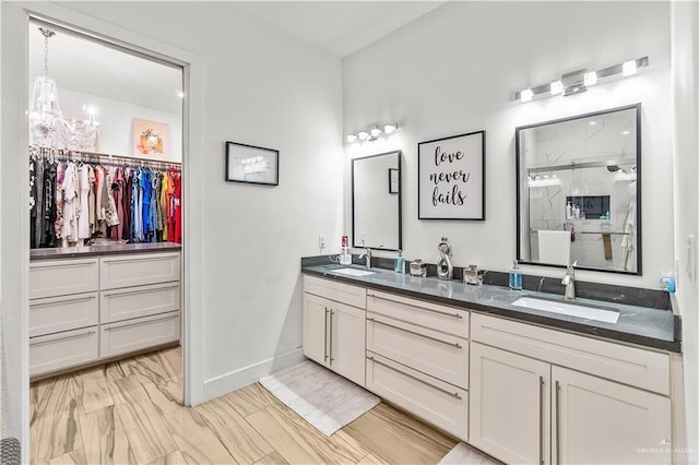 full bathroom featuring an inviting chandelier, double vanity, a shower stall, and a sink