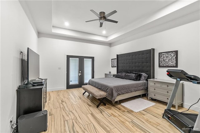 bedroom with a tray ceiling, french doors, light wood finished floors, and access to exterior