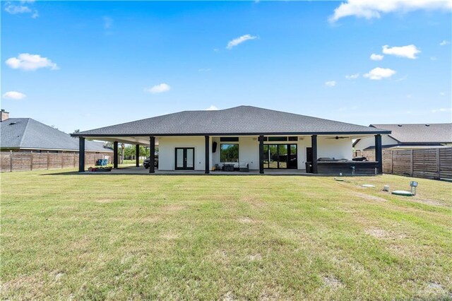 rear view of house with a yard, a fenced backyard, a ceiling fan, a patio area, and french doors