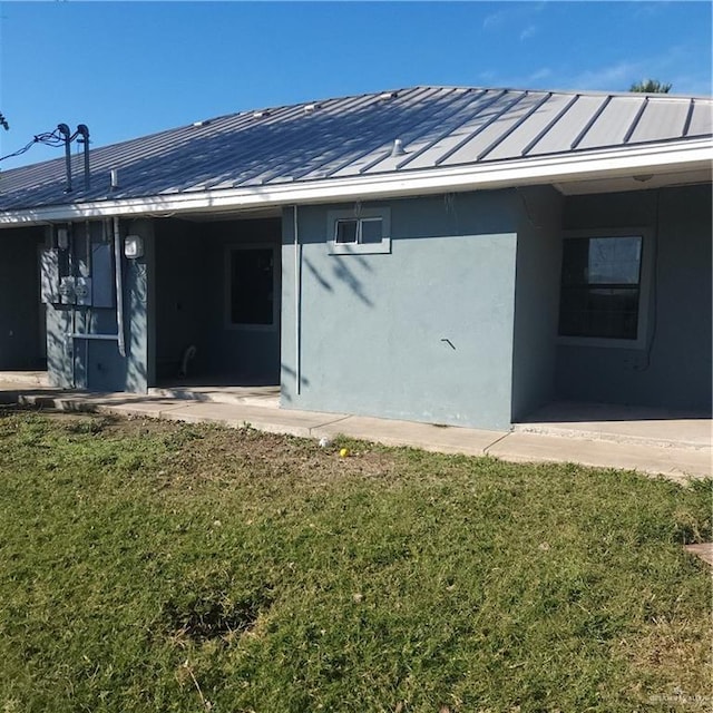 back of property with a carport and a lawn