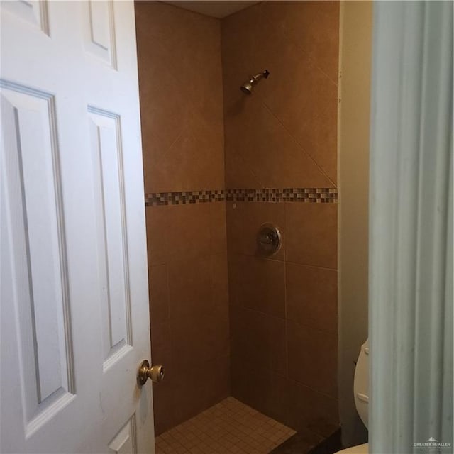 bathroom featuring a tile shower and toilet