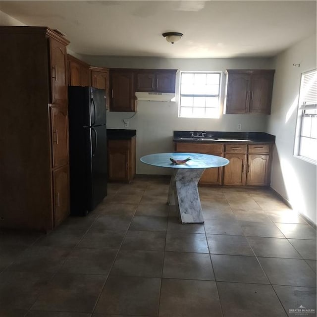 kitchen featuring sink, black fridge, and dark tile patterned flooring