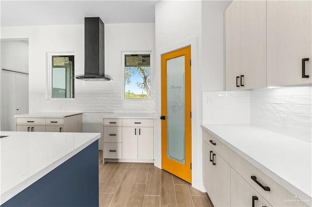 kitchen featuring tasteful backsplash, range hood, light countertops, and wood tiled floor