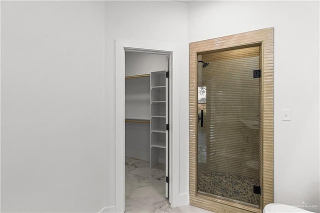 bathroom with marble finish floor, a stall shower, and a spacious closet