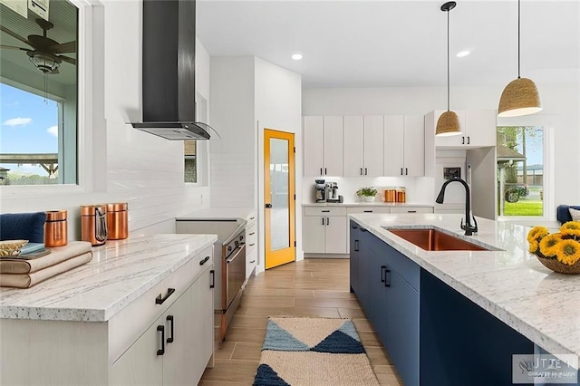 kitchen with a wealth of natural light, decorative backsplash, wall chimney exhaust hood, high end stainless steel range, and a sink