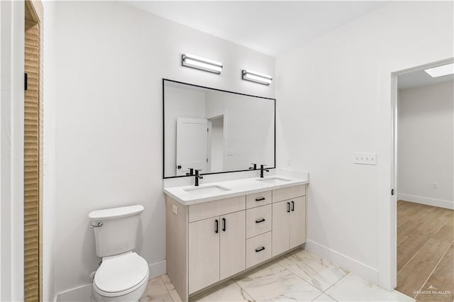 bathroom featuring toilet, baseboards, and a sink