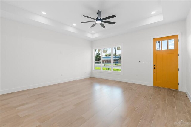 foyer with a raised ceiling, a ceiling fan, recessed lighting, light wood finished floors, and baseboards