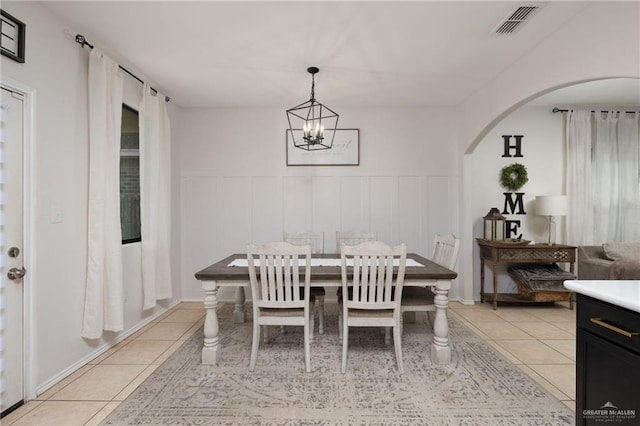 3517 Prestwick St, Edinburg, TX 78542 - dining room featuring light tile patterned flooring, arched walkways, a chandelier, a wainscoted wall, and a decorative wall