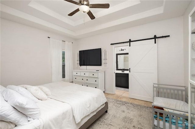 3517 Prestwick St, Edinburg, TX 78542 - bedroom featuring a raised ceiling, a barn door, light tile patterned flooring, a ceiling fan, and ensuite bathroom