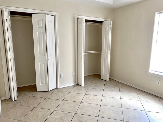 unfurnished bedroom featuring multiple windows and light tile patterned flooring