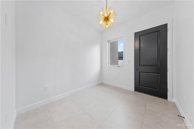 empty room featuring a notable chandelier and light tile patterned floors