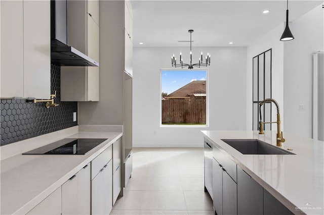 kitchen featuring white cabinetry, black electric cooktop, sink, and hanging light fixtures