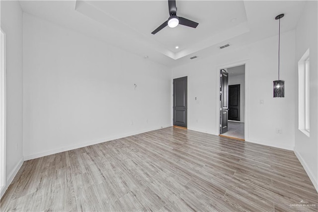 unfurnished room featuring a tray ceiling, light hardwood / wood-style floors, and ceiling fan