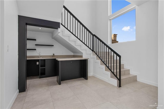 stairs with a towering ceiling and tile patterned floors