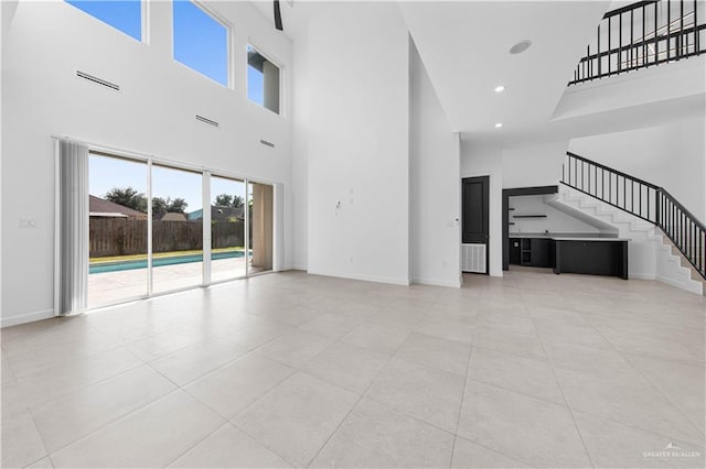 unfurnished living room with a high ceiling and light tile patterned flooring