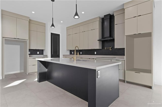 kitchen featuring sink, backsplash, hanging light fixtures, a center island with sink, and wall chimney exhaust hood