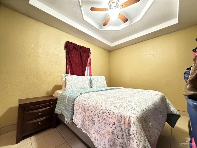 tiled bedroom with a raised ceiling and ceiling fan