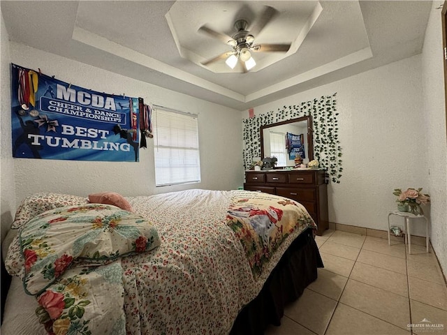 tiled bedroom featuring a raised ceiling and ceiling fan