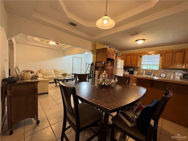 tiled dining room with a tray ceiling