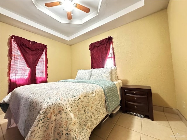 bedroom featuring tile patterned flooring, ceiling fan, and a raised ceiling