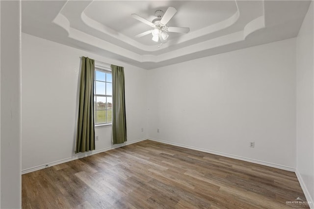 unfurnished room featuring ceiling fan, a tray ceiling, and hardwood / wood-style floors