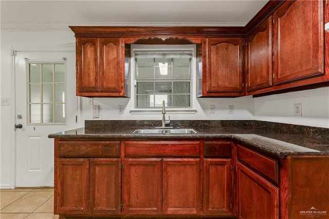 kitchen featuring light tile patterned floors, dark stone countertops, ornamental molding, and sink