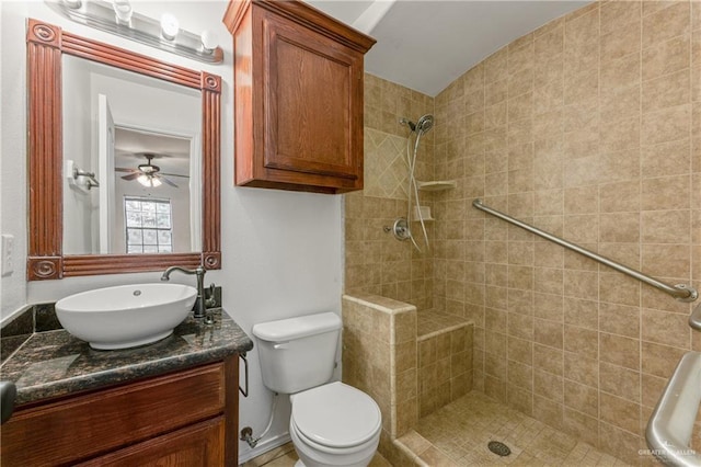 bathroom with toilet, a tile shower, and vanity