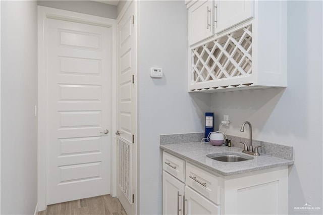 6907 N 11th Ln, Mcallen, TX 78504 - kitchen featuring a sink, white cabinetry, light wood-style flooring, and light stone countertops