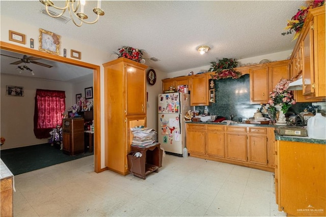 kitchen featuring ceiling fan with notable chandelier, white fridge, and a textured ceiling