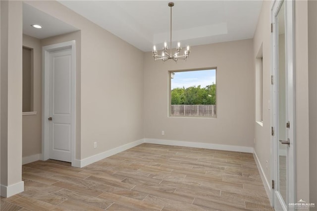 unfurnished room featuring an inviting chandelier and light hardwood / wood-style flooring