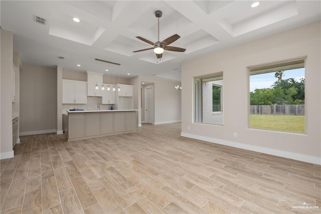 unfurnished living room with ceiling fan with notable chandelier, beamed ceiling, light wood-type flooring, and coffered ceiling