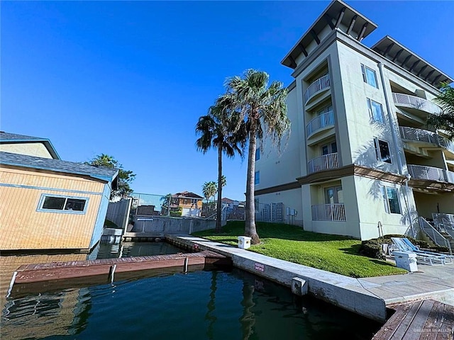 view of dock with a water view and a lawn