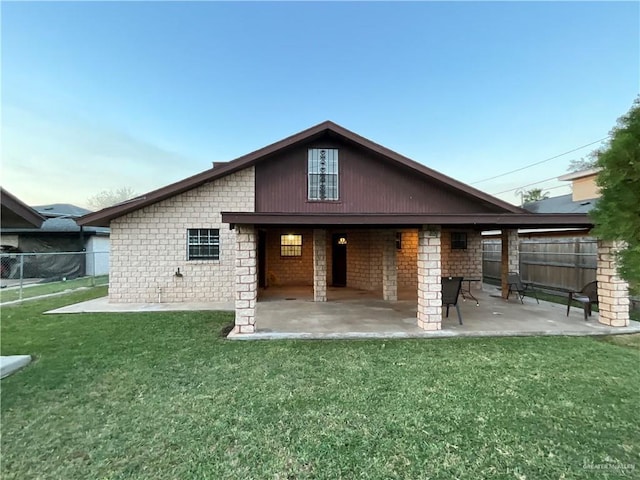 rear view of house with fence, a lawn, and a patio