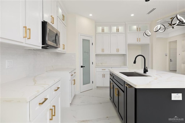 2809 E Tamarindo Ave, Hidalgo, TX 78557 - kitchen with stainless steel microwave, white cabinets, glass insert cabinets, light stone countertops, and recessed lighting