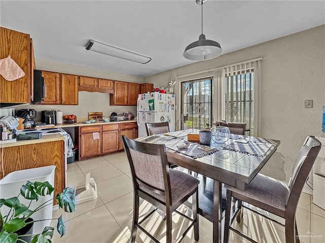 kitchen with white fridge, light tile patterned flooring, and hanging light fixtures