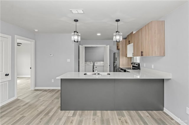 kitchen featuring stainless steel range with electric stovetop, light hardwood / wood-style floors, independent washer and dryer, and kitchen peninsula