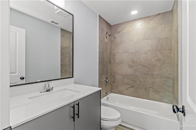 full bathroom with vanity, tiled shower / bath combo, and toilet