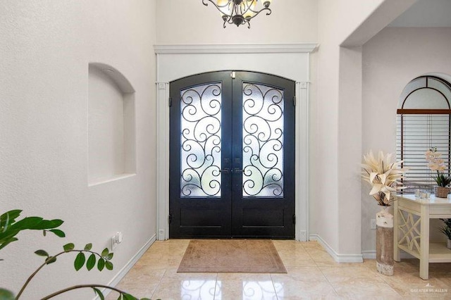 tiled foyer entrance featuring a chandelier and french doors