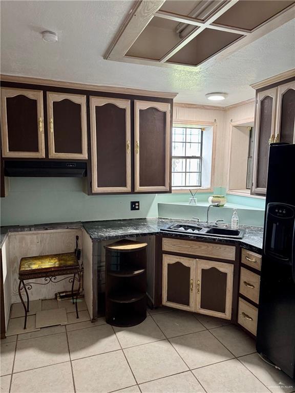 3813 N Taylor Rd, Mission, TX 78573 - kitchen featuring black refrigerator with ice dispenser, under cabinet range hood, extractor fan, light tile patterned flooring, and a textured ceiling