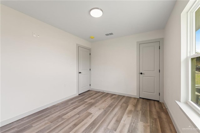 empty room with light hardwood / wood-style flooring and a healthy amount of sunlight