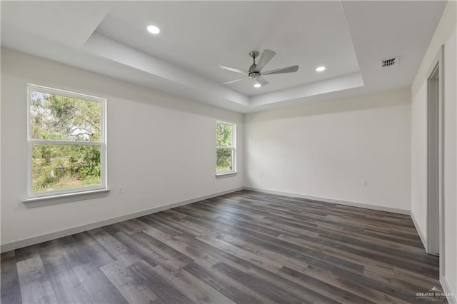 unfurnished room featuring dark hardwood / wood-style floors, a raised ceiling, and ceiling fan