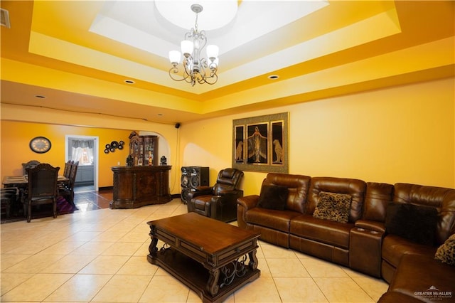 living room with an inviting chandelier, light tile patterned floors, and a tray ceiling