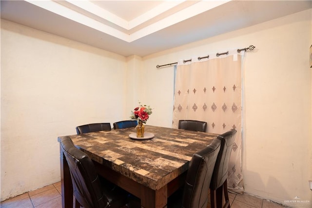 dining room featuring light tile patterned floors and a tray ceiling