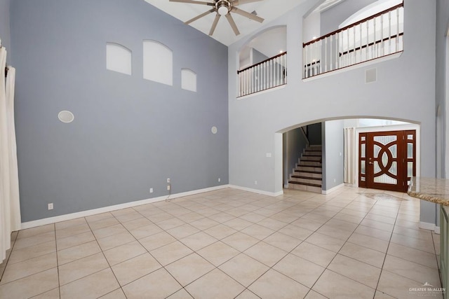 3222 Princess St, Edinburg, TX 78539 - unfurnished living room featuring ceiling fan, a towering ceiling, light tile patterned flooring, stairway, and baseboards