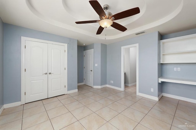 3222 Princess St, Edinburg, TX 78539 - unfurnished bedroom with a tray ceiling, a closet, light tile patterned floors, a ceiling fan, and baseboards